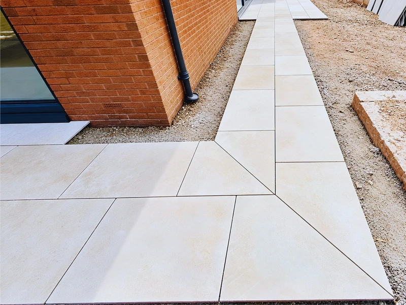 A bespoke mitred corner in pale stone paving, where two paving runs meet at an angle against the house
