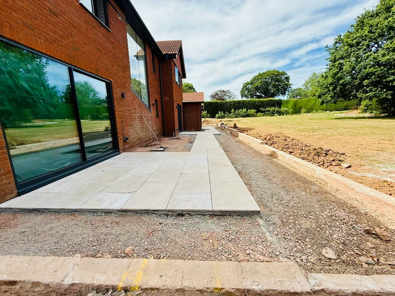 The finished paving running the length of the house, looking out over the newly turfed lawn beyond