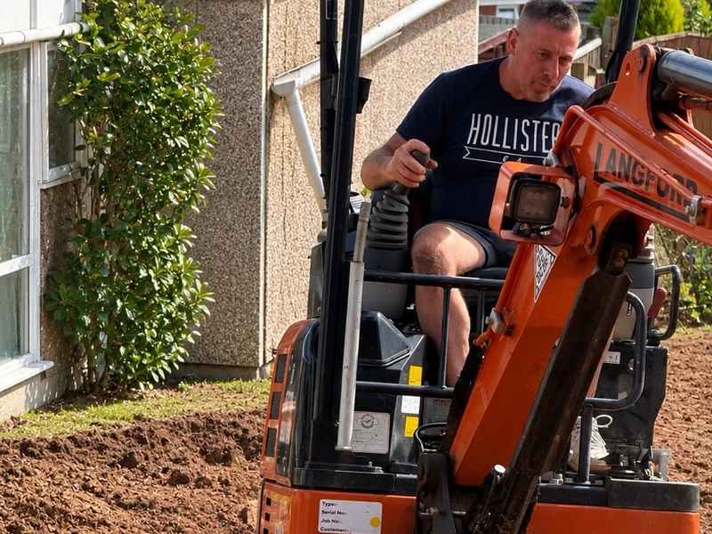 Graham operating a mini digger, cutting the first trench into freshly excavated ground