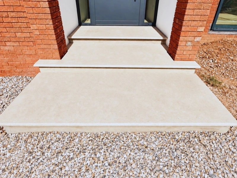 Pale stone steps up to a front door, edged in brick with a pebble border either side